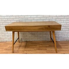 a wooden table sitting on top of a hard wood floor next to a brick wall