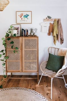 a living room with wicker furniture and plants on the wall next to a wooden cabinet