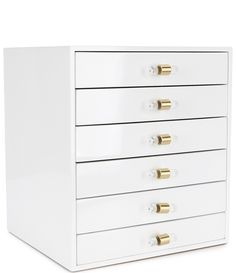 a white chest of drawers with gold handles and knobs on each drawer, against a white background