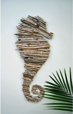 a seahorse made out of driftwood next to a palm leaf on the wall