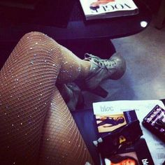 a woman's legs in fishnet stockings and heels on a table with magazines