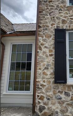 a stone building with two windows and black shutters