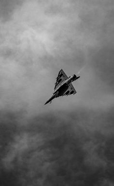 a fighter jet flying through a cloudy sky