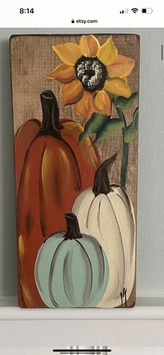 a painting of three pumpkins and a sunflower on a shelf with text overlay