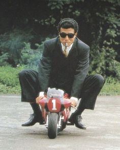 a man riding on the back of a red motorcycle