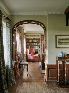 an arched doorway leads to a sitting area with chairs and bookshelves on either side