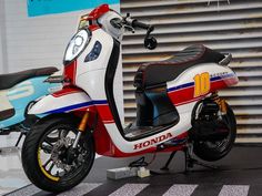 a red, white and blue scooter parked in front of a garage door