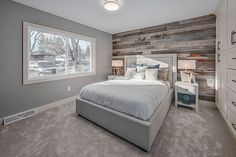 a bedroom with a bed, nightstands and two windows in the room that have wood paneling on the walls