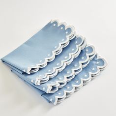 four blue napkins with white scalloped edges are stacked on top of each other