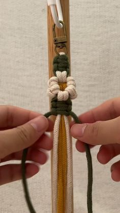 two hands are holding an object made out of yarn