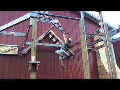 a man on a skateboard doing tricks in front of a red building with wooden beams