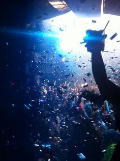 a person holding up a cell phone in front of confetti falling from the ceiling