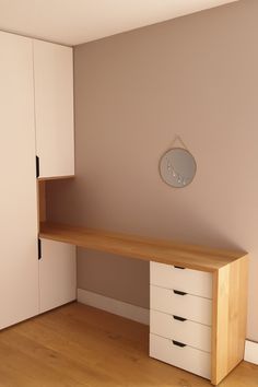 an empty room with a wooden desk and white cupboards in front of the wall