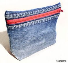 a blue denim pouch with red zippers on the bottom and inside, sitting on a white surface