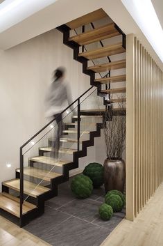 there is a man walking down the stairs in this modern house with wood and glass railings