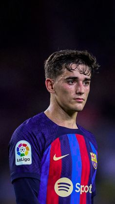 a young man in a soccer uniform looks at the camera while standing with his hands on his hips