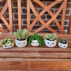 three crocheted potted plants sitting on top of a wooden bench