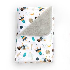 a baby blanket with space and rockets on it, next to a bottle of milk