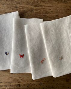 four white linen napkins with embroidered animals on them