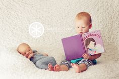 two babies are laying on the floor and reading books to each other while one is holding a book