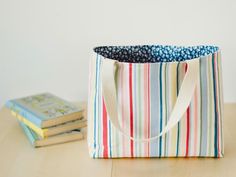 a bag sitting on top of a wooden table next to a stack of books and a book