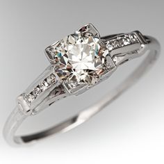 an antique style diamond engagement ring with channeled shoulders and side stones in white gold