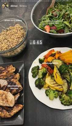 a table topped with plates of food next to bowls of salad and chicken on top of it