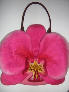 a pink flower on a white surface with a brown handle and leather strap around it