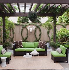 an outdoor living area with green couches and pillows