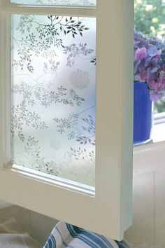 a window with frosted glass on the outside and flowers in the inside behind it