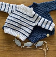 two knitted sweaters sitting on top of a wooden table