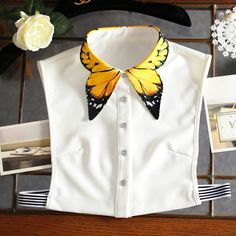 a white shirt with a yellow butterfly on the collar and black striped cuffs, along with other items