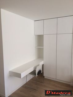 an empty room with white cupboards and shelves on the wall next to a wooden floor