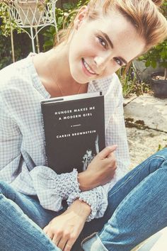 a woman sitting on the ground holding a book