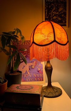 a lamp sitting on top of a table next to a book and potted plant