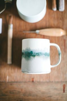 a coffee cup sitting on top of a wooden table next to other kitchen utensils