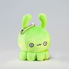 a green stuffed animal with a tiara on it's head, sitting in front of a gray background