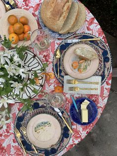 the table is set with bread, oranges, and other food on it's plates