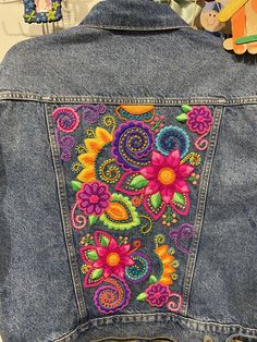 the back of a jean jacket with embroidered flowers on it