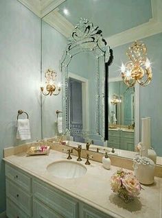 a bathroom vanity with a large mirror and chandelier over it's sink