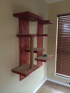 a cat tree in the corner of a room with blinds on the window sill