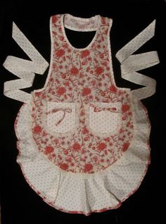 an apron with red flowers and white ruffles on the bottom is sitting on a black surface