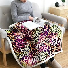 a woman sitting in a chair with a blanket on her lap, reading a book