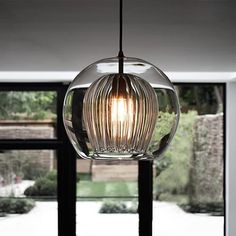 a glass light hanging from a ceiling in a living room next to a large window