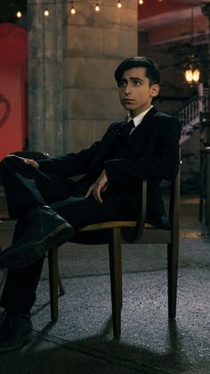 a young man sitting on top of a wooden chair in a room filled with lights