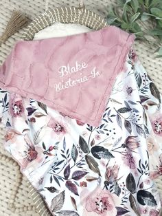 two blankets with pink and white flowers on them, one has a name written on it