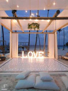 an outdoor wedding setup with love written on the floor and white drapes over it