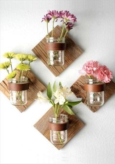 three vases with flowers in them are hanging on the wall and one is made out of wood