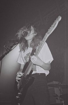 a woman with long hair playing an electric guitar in front of a microphone on stage