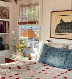 a bed sitting in a bedroom next to a window with a lamp on top of it